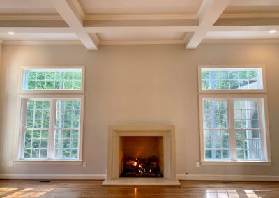 Living room with white walls, two large windows, and a fireplace.