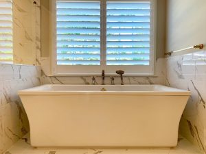 Large bathtub with shower head attachment | Quaker Custom Homes, LLC A large white bathtub with a window above. There is a shower head attached next to the faucet.