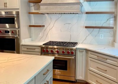 White marble and grey wood kitchen with a gas stove and hood vent.