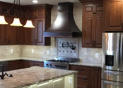 A kitchen with dark and light brown accents. There is a large island in the center.