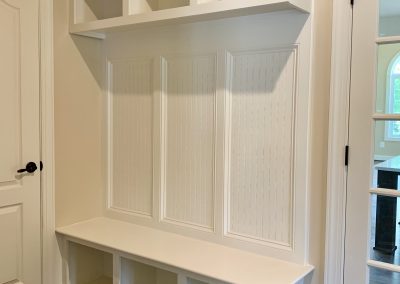 A white bench with storage above and below, next to an entrance door.