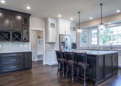 Dining area and kitchen with dark brown cabinets and stools.